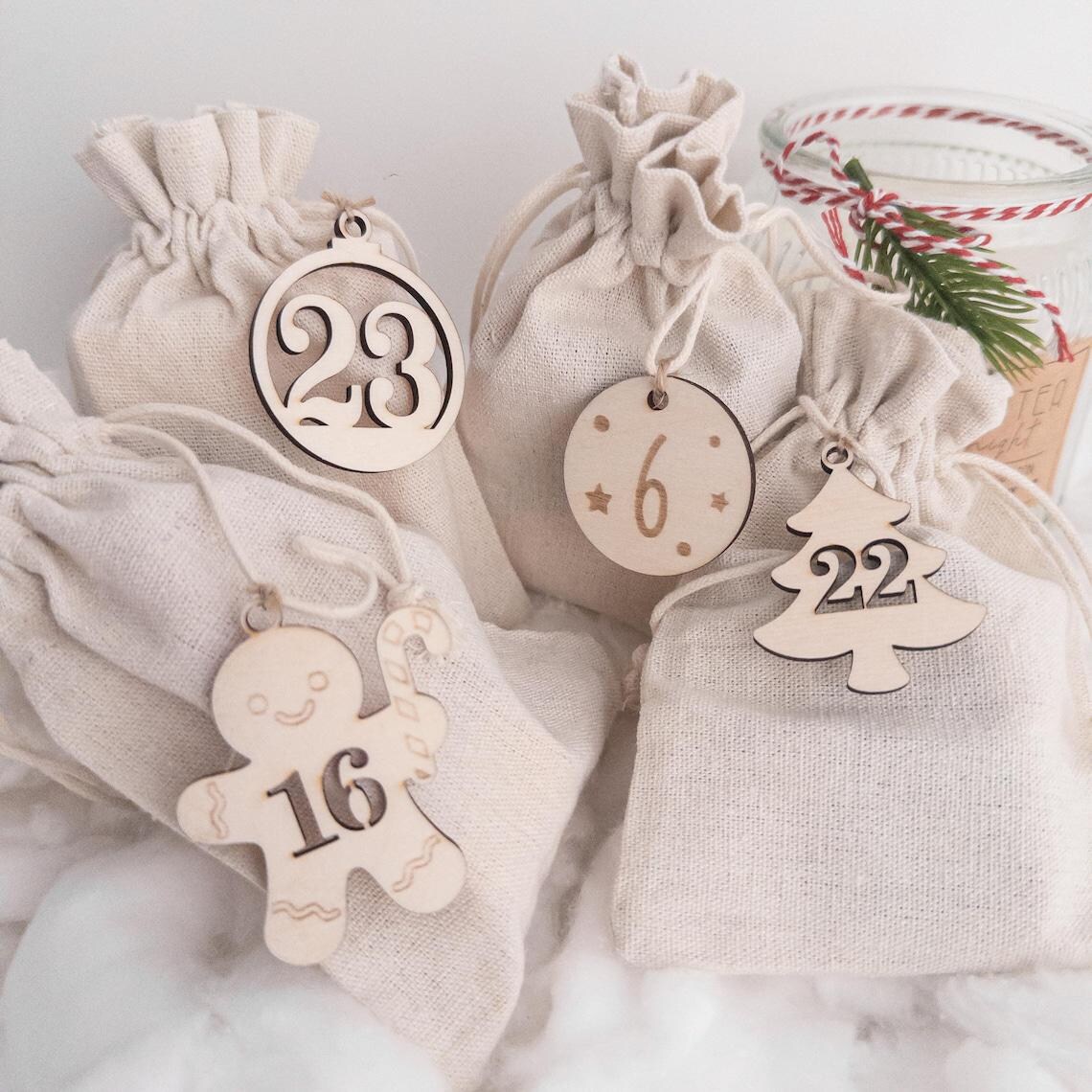 Nahaufnahme Adventskalender-Set: nummerierte Holzanhänger und Stoffbeutel in Naturtönen, nachhaltig und jährlich verwendbar.