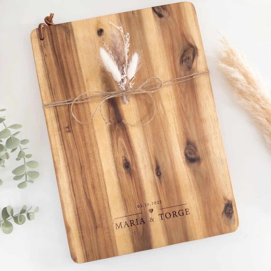 Personalisiertes Schneidebrett mit Namen aus Akazienholz mit Gravur „Maria & Torge – 02.10.2025“, dekoriert mit Juteband und Trockenblumen – Hochzeitsgeschenk.