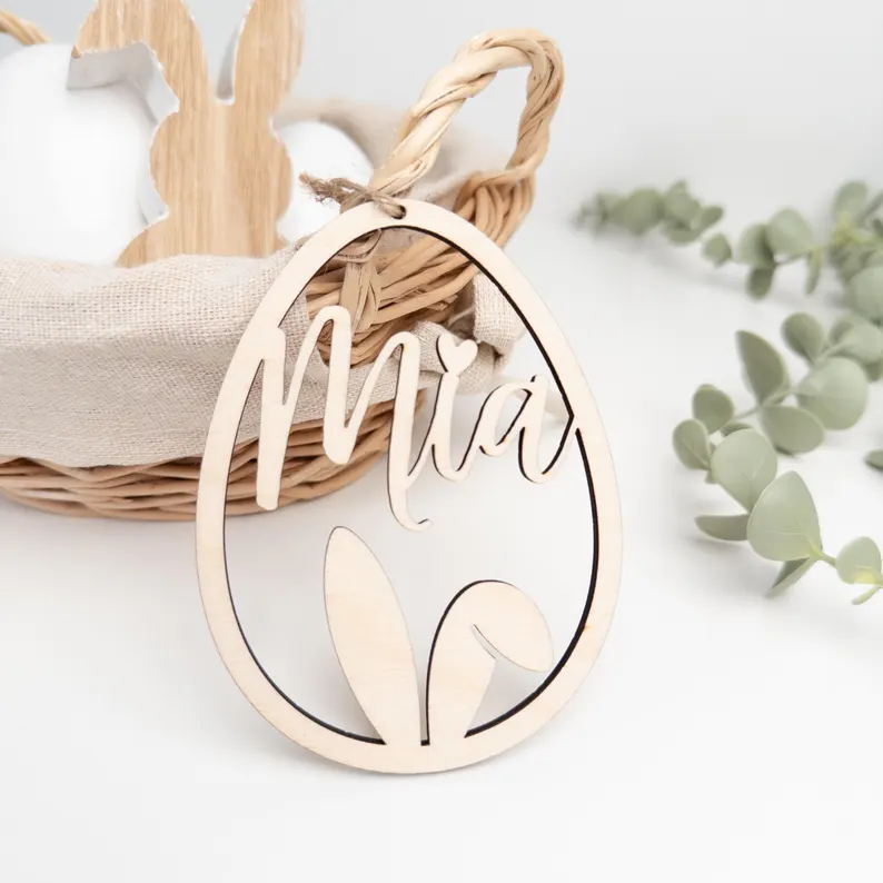 Personalisierter Osteranhänger aus Holz (Eierform) mit Name „Mia“ und Hasenohren, Deko am Weidenkorb im hellen Scandi-Stil.